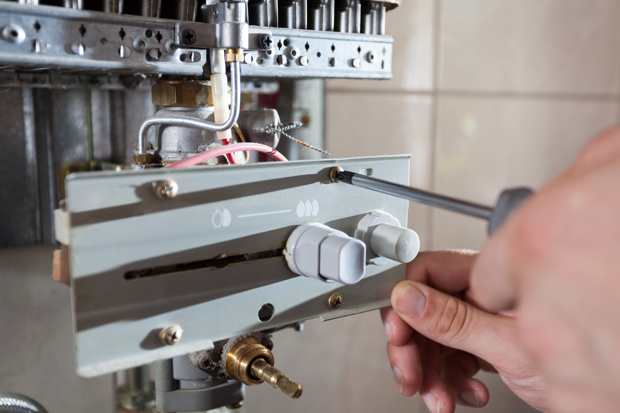 Plumber fixing a gas water heater with screwdriver